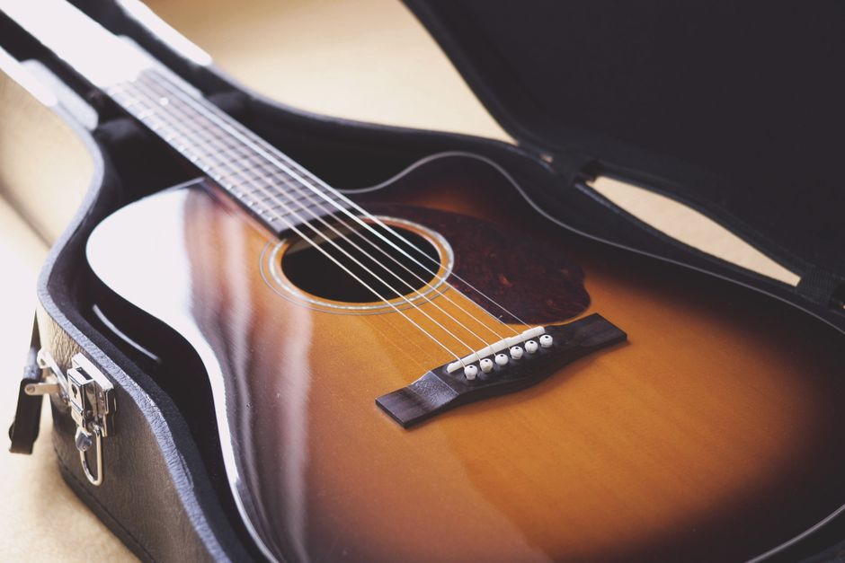 A close-up photo of a vintage acoustic guitar in a hard case, showcasing its elegant design and wood grain.