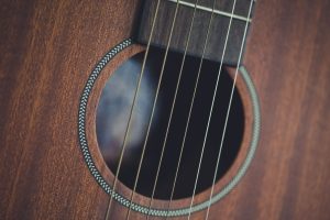 Close-up of the soundhole, rosette and steel strings on a mahogany-topped acoustic guitar