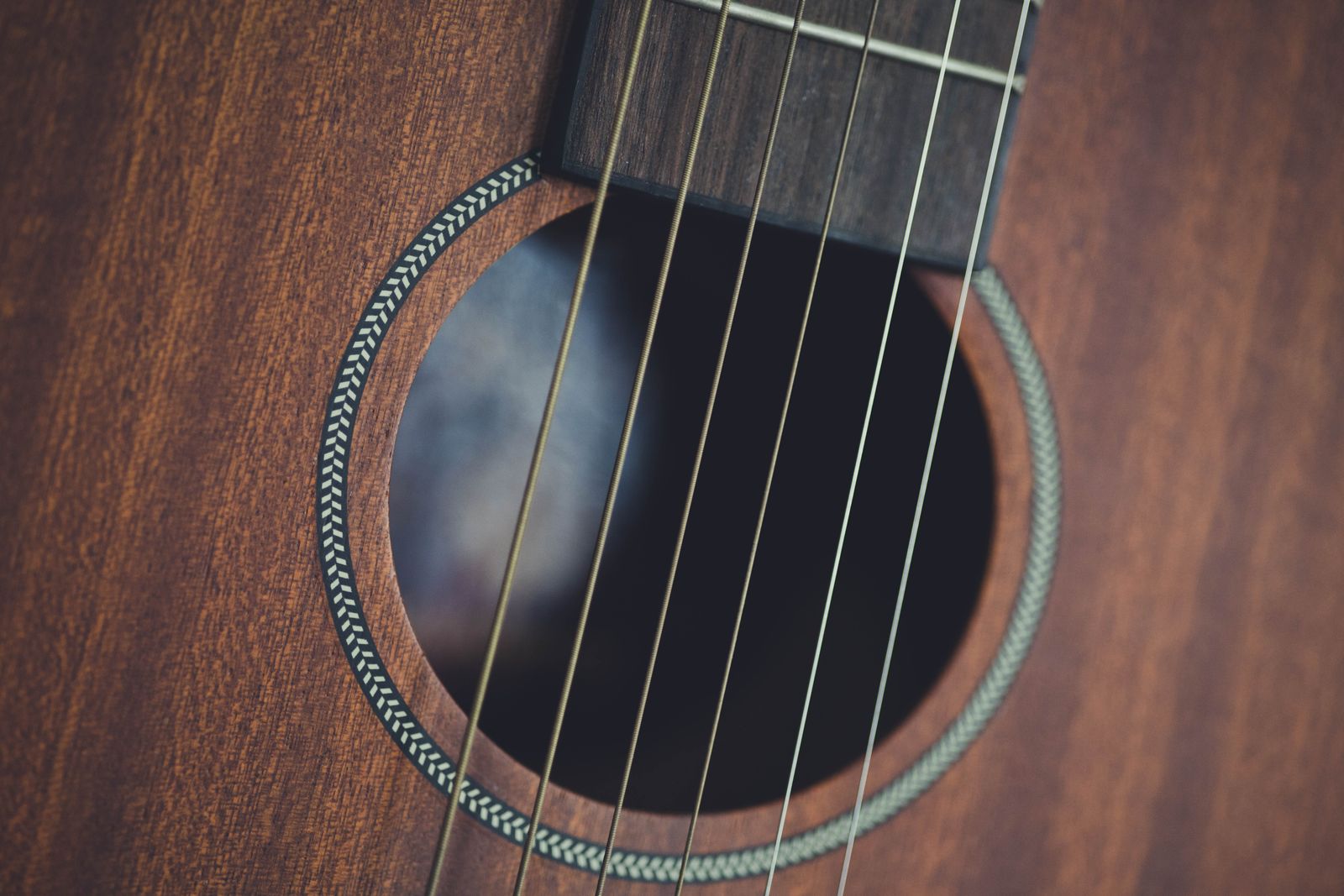 Close-up of the soundhole, rosette and steel strings on a mahogany-topped acoustic guitar