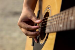 Detailed view of a hand strumming an acoustic guitar outdoors, capturing musical passion.