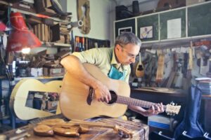 Middle-aged man playing an acoustic guitar in a woodworking workshop.