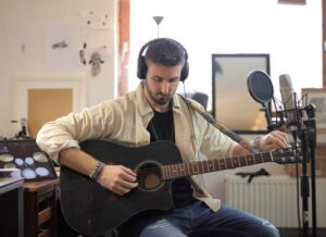 Musician adjusting guitar strings in modern recording studio environment.